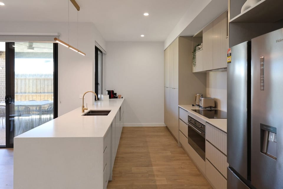 Sleek modern kitchen with long island, stainless steel appliances, and ample bench space