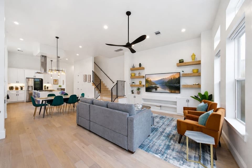 Elegant open living space featuring high ceilings, designer furnishings, shuffleboard table, and modern chef’s kitchen. Relax w/the large 75-inch TV while natural light pours through expansive windows. Plus the couch doubles as a queen sleeper sofa.