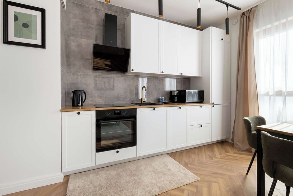 A compact kitchenette wall with integrated oven and minimalist white cupboards. The space looks tidy and efficiently organized.