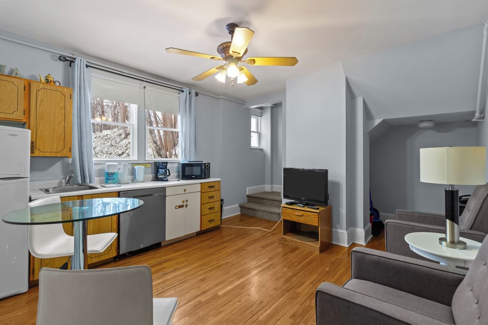 Open-concept kitchen and dining area with full appliances, large windows, and warm hardwood flooring.