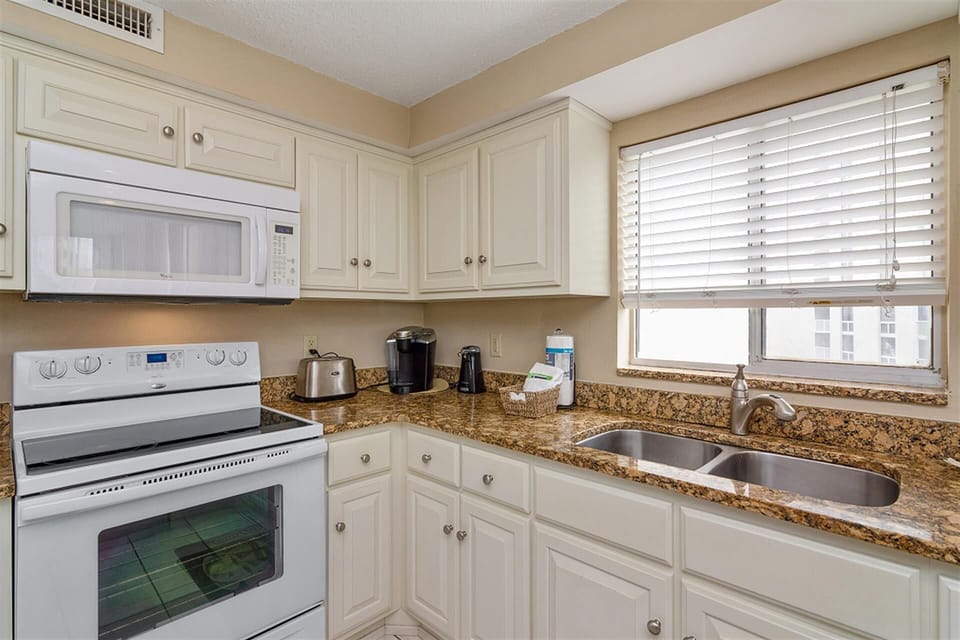 Your fully equipped kitchen features granite countertops, white appliances, and everything needed to prepare meals during your stay.