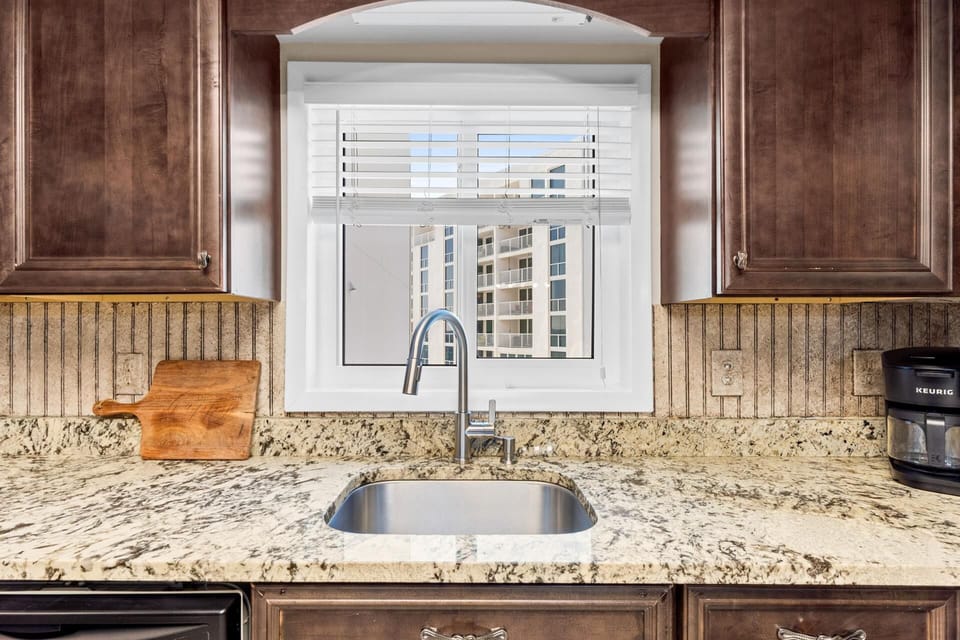 Prepare your favorite meals in this elegant kitchen featuring granite countertops, modern appliances, and a lovely window view.