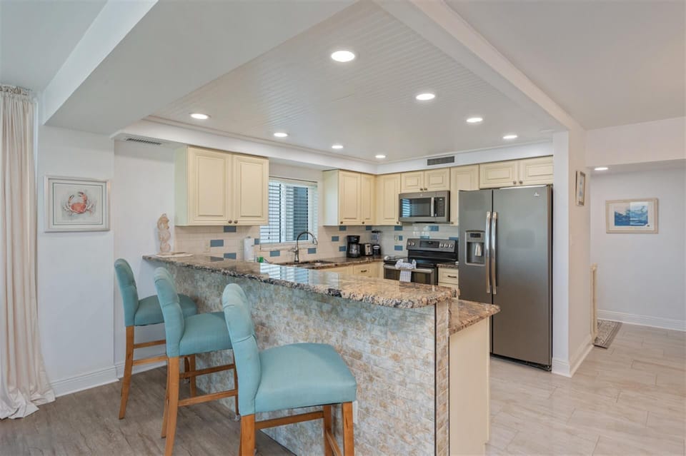 Your fully equipped kitchen awaits with granite counters, stainless appliances, and breakfast bar seating for casual coastal dining.