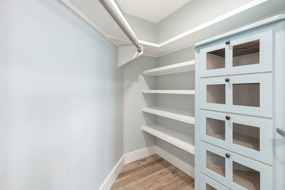 Your private walk-in pantry offers organized storage with built-in shelving and glass-front cabinets for all your culinary essentials.