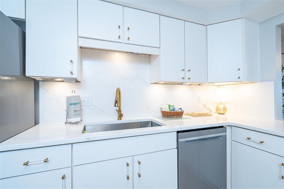 Your bright, modern kitchen features pristine white cabinetry, sleek countertops, and warm under-cabinet lighting for comfortable meal prep.