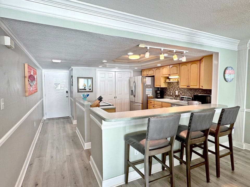 Your open-plan kitchen features warm wood cabinets, granite counters, and a breakfast bar where you can enjoy morning coffee or casual meals together.