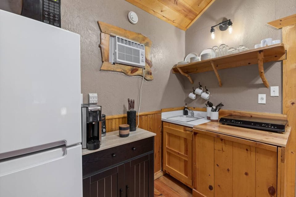 Fully stocked cabin kitchenette with mini fridge, microwave, coffee maker, dishes, and sink.