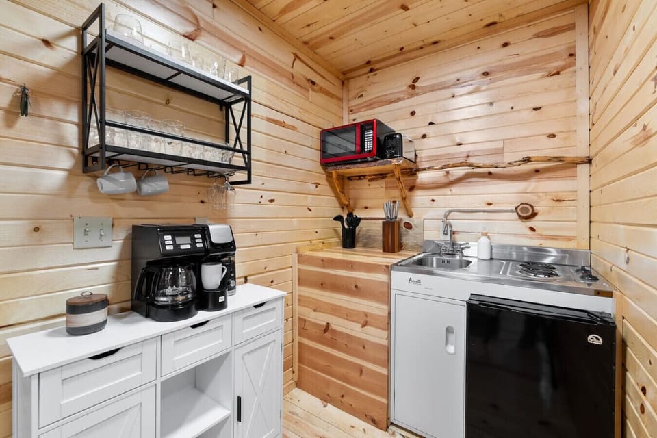 Simple and functional kitchenette with sink, mini fridge, microwave, and coffee setup for easy meals and mornings in.