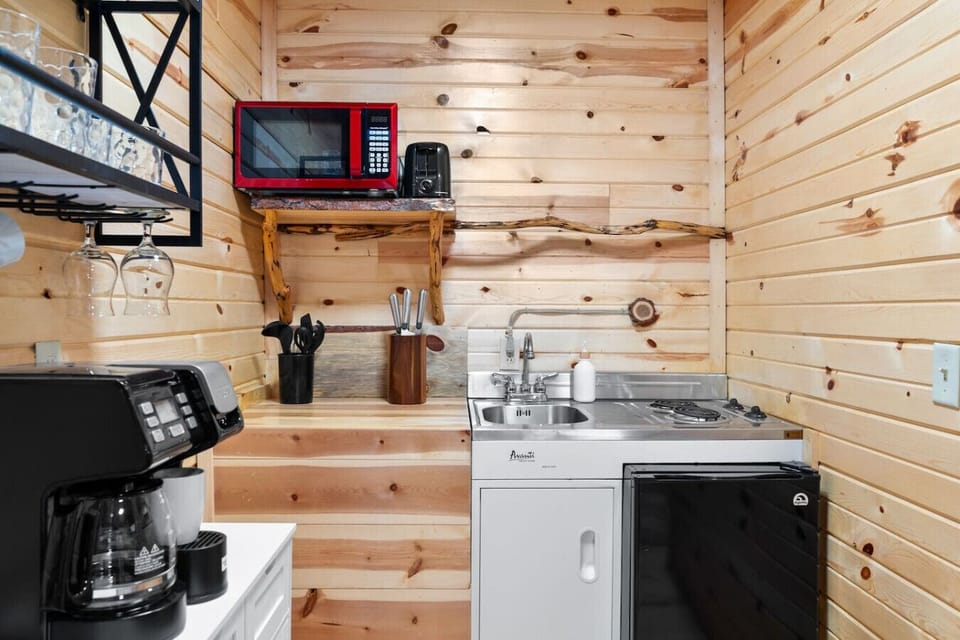 Compact and well-equipped kitchenette with sink, mini fridge, microwave, coffee maker, and basic cooking essentials.