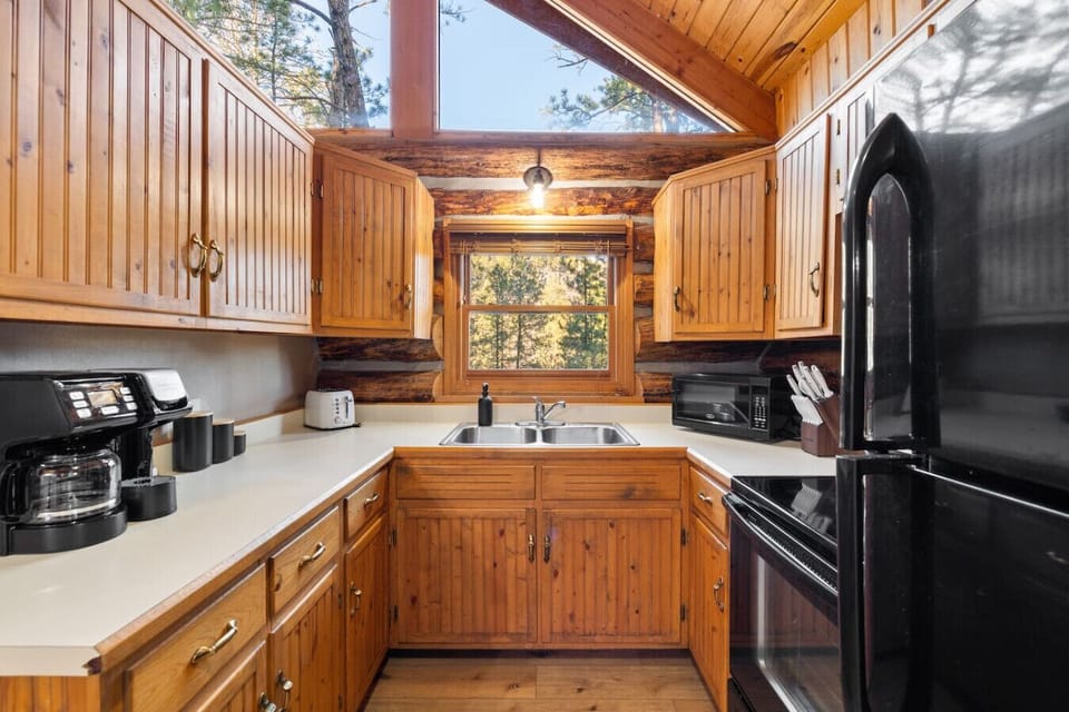 Full kitchen with refrigerator, stove, microwave, coffee maker, and log cabin charm.