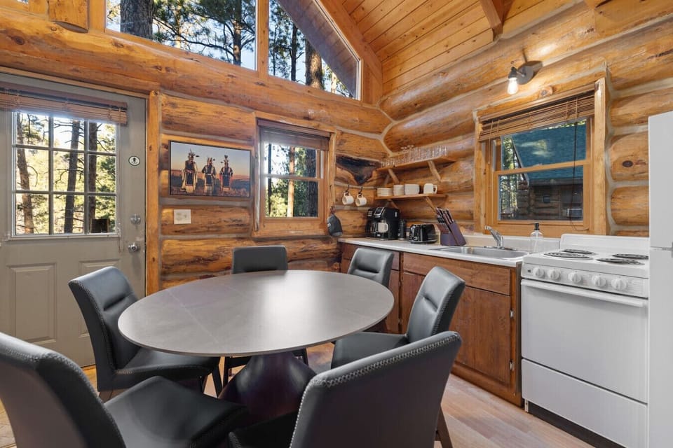 Sunlit cabin kitchen with essentials for home-style cooking. Enjoy breakfast with a view of pine trees through the large windows.