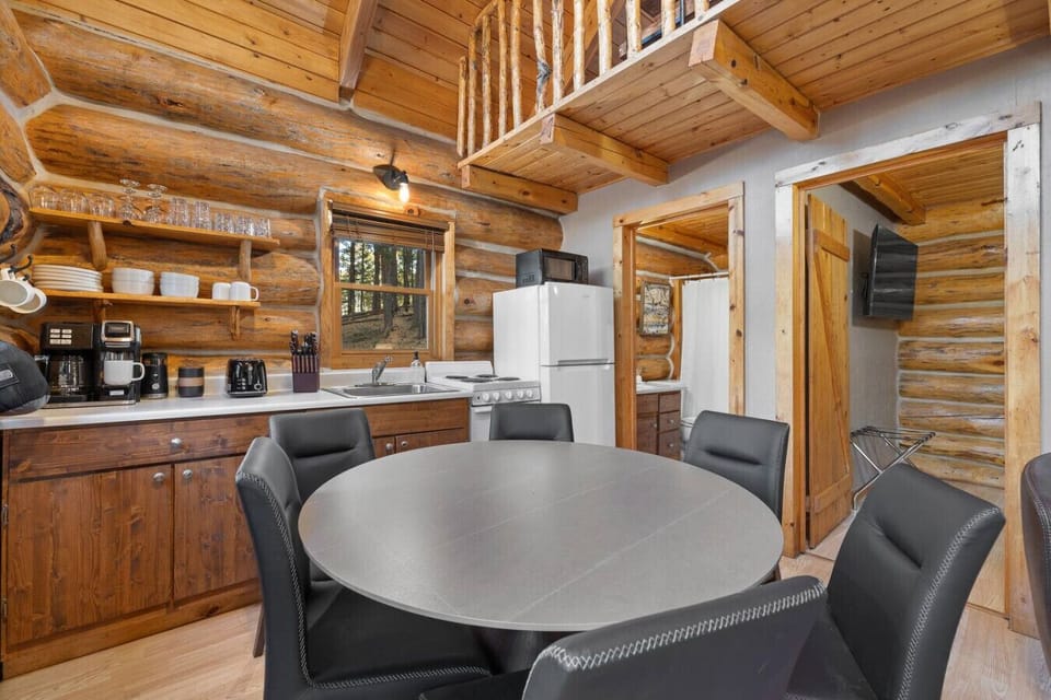 Gather in a full kitchen with modern appliances, dining table, and forest views. Your Hillside Country Cabin home base for shared meals and morning coffee.