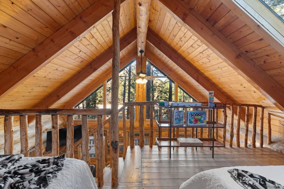 Scenic loft with natural light and forest views. Overlooks the cozy living room below for an open, airy cabin feel.