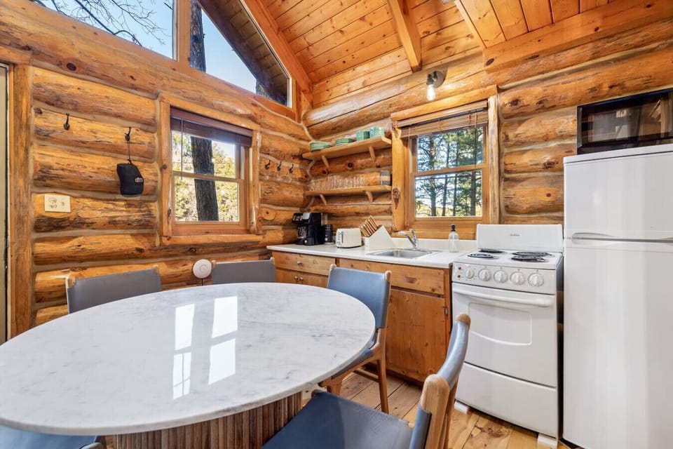 Open concept log cabin kitchen and dining area with seating and natural light in the Black Hills.