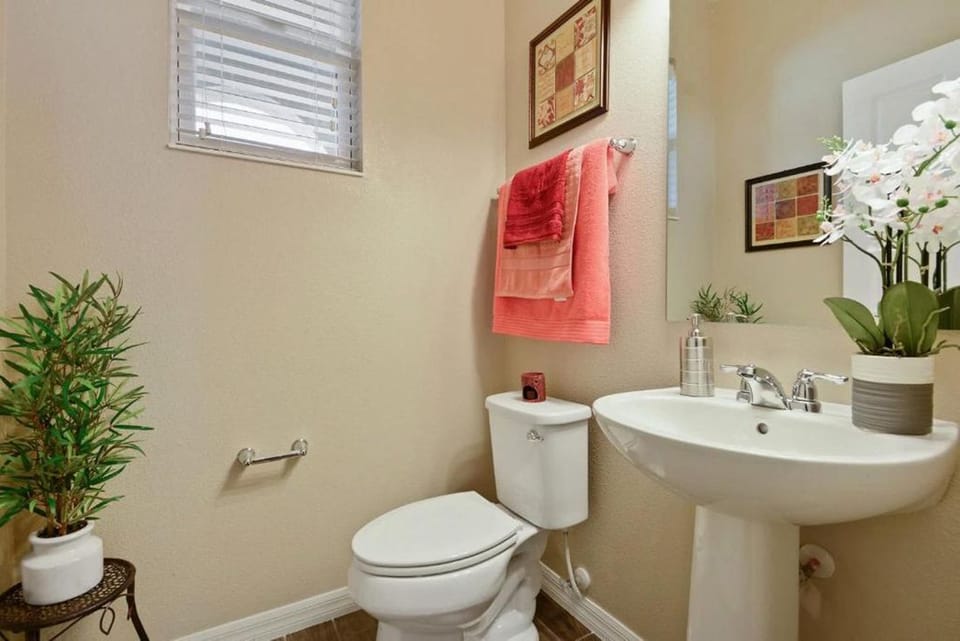 A neutral half bathroom with a white pedestal sink and toilet.