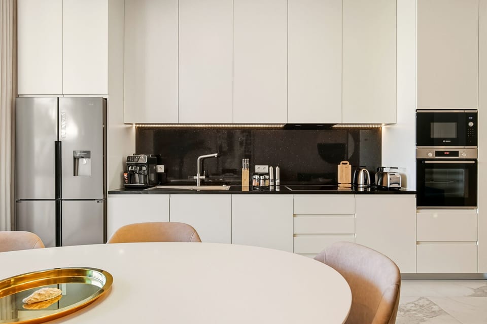 Fully equipped open plan kitchen with state-of-the-art appliances, including washing machine, refrigerator, freezer, coffee maker, oven, deep fryer, microwave, toaster, and kettle. All necessary kitchen utensils are available to prepare delicious meals.