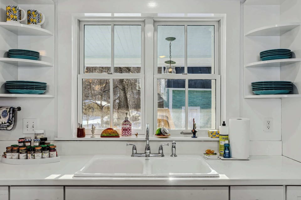 Kitchen sink beneath a window framing the wooded yard