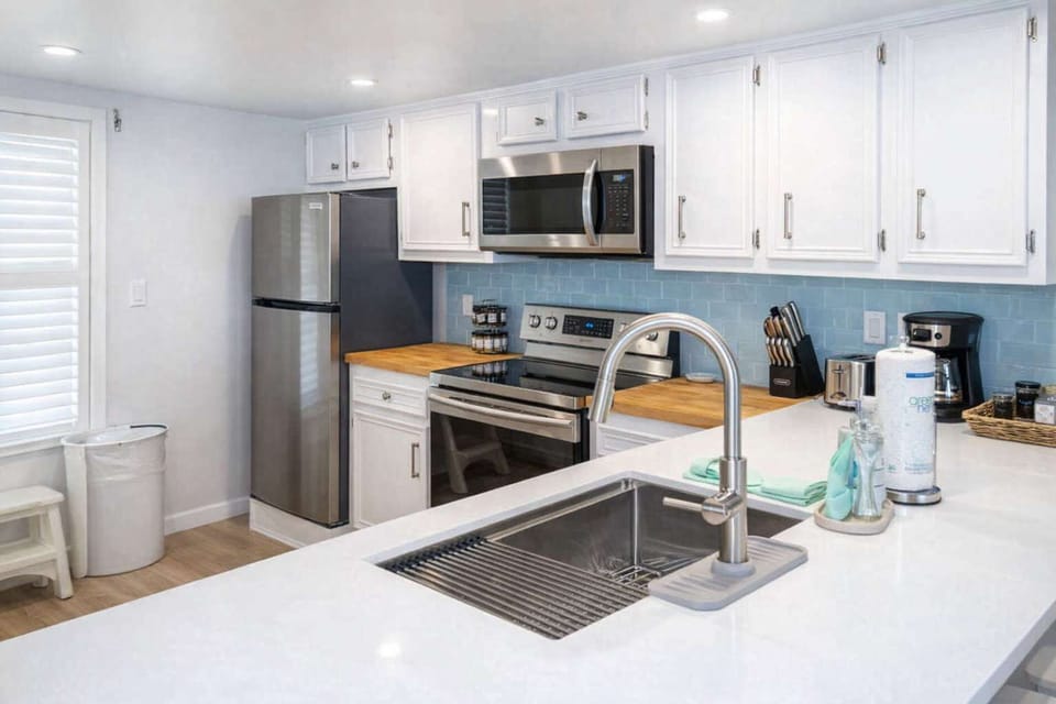 Bright, modern kitchen with stainless steel appliances, butcher block counters, subway tile backsplash, and natural light—perfect for cooking and entertaining in a clean, stylish space.