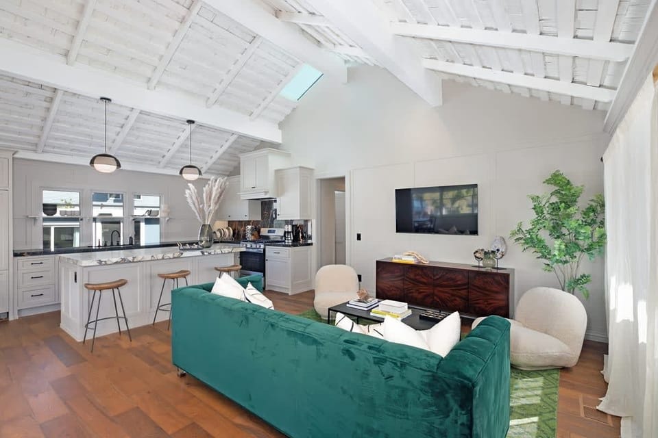 This open-concept living area blends comfort and style, featuring a sofa, clean ceilings, and easy access to the modern kitchen.