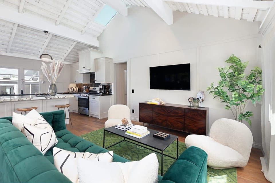 Relax in this living area, where a sofa and cozy swivel chairs meet high ceilings. The open layout flows seamlessly into the kitchen, making it the perfect spot for movie nights or post-beach lounging.