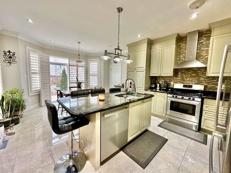Elevated kitchen with a Centre Island featuring high chairs and a stainless steel Gas Stove complete with an inbuilt Oven, merging style and culinary prowess effortlessly.