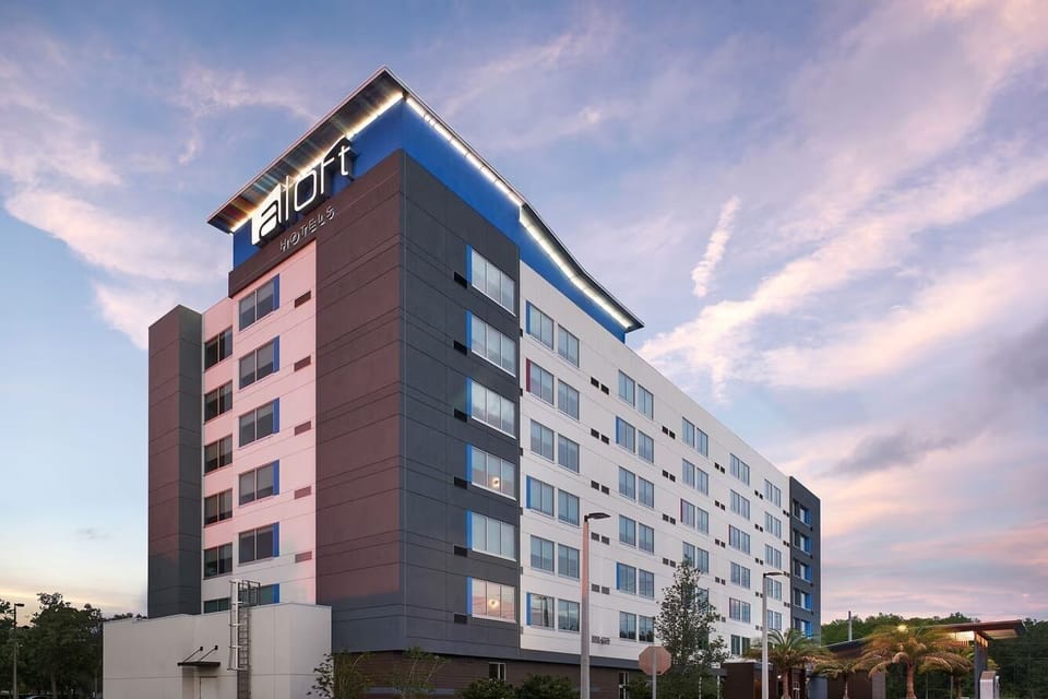 Arrive to a sleek, modern hotel façade at sunset.