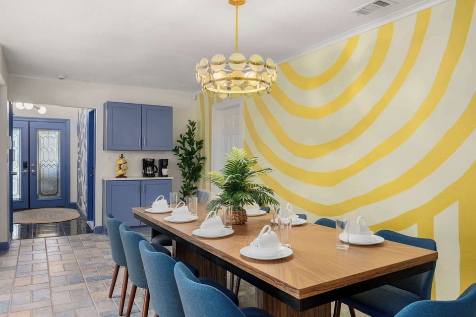 Dining space w/ a long wood table, set & ready for a group meal.
