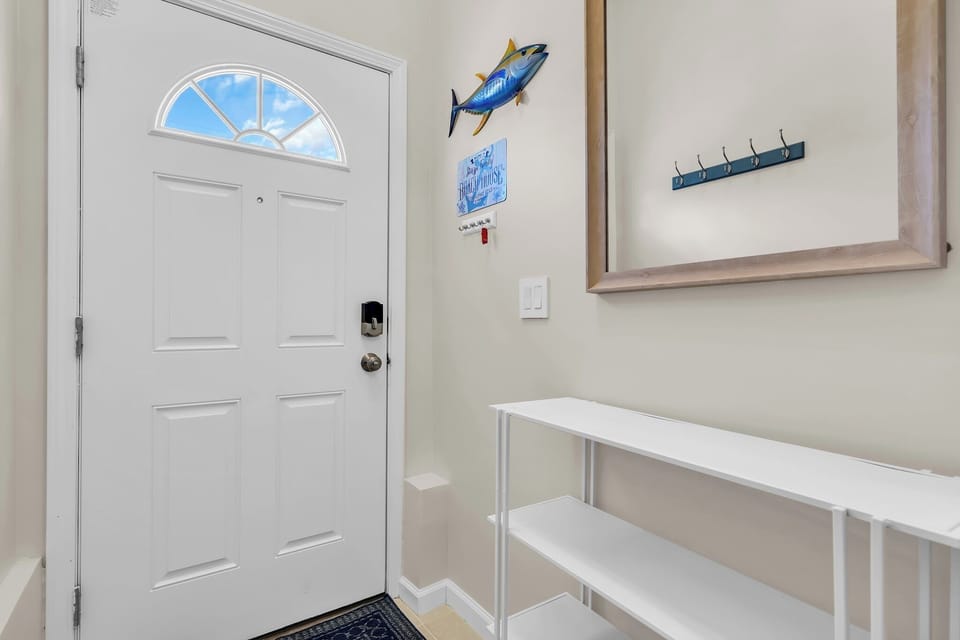 Bright coastal entryway with mirror, hooks, and handy storage shelf