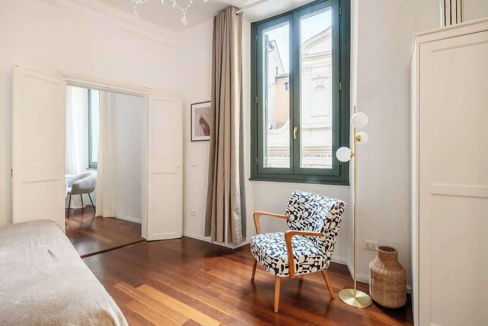 Sunlit room with tall windows, hardwood floors, and a chic patterned chair.