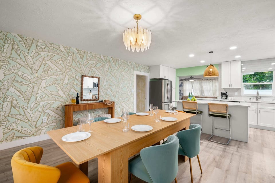Elegant dining room w/ chandelier, long table & mustard chairs.
