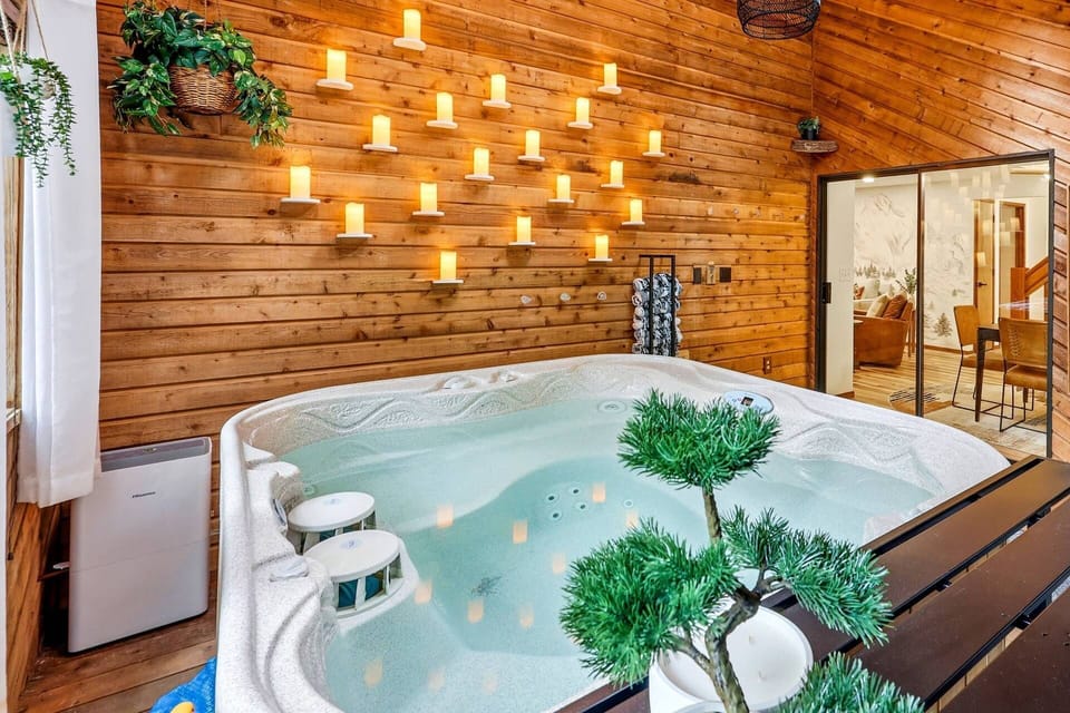 An inviting indoor spa room featuring a multi-person hot tub set against a wood-paneled wall decorated with ambient candle lighting.