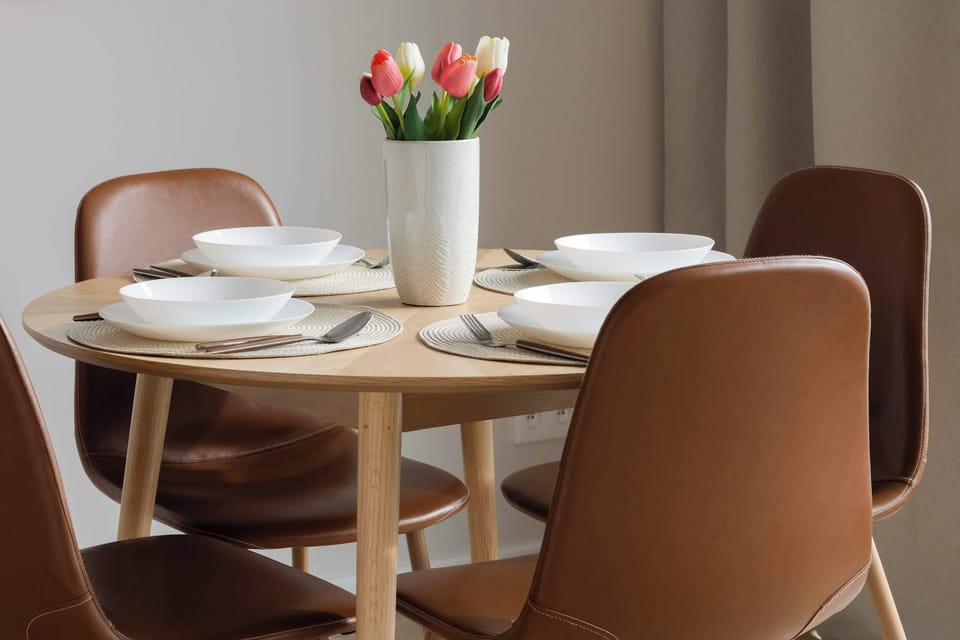 Another dining angle showing tableware and a vase of flowers as a centerpiece. The chairs and neutral décor create a warm dining corner. The area appears thoughtfully arranged.