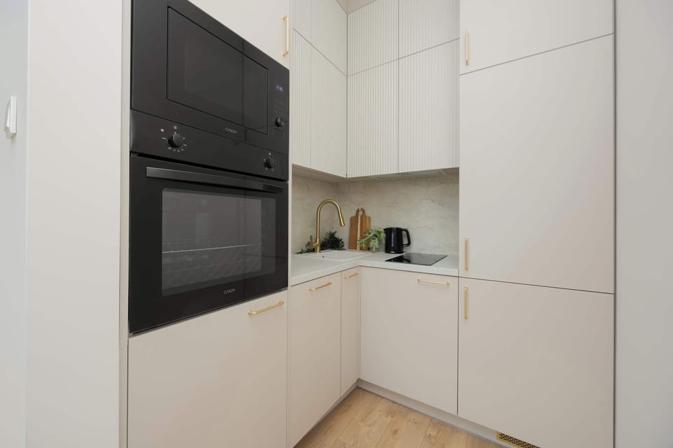A compact kitchen with tall white cabinetry and built-in appliances. Clean lines and minimal design dominate the space. The layout feels efficient and modern.
