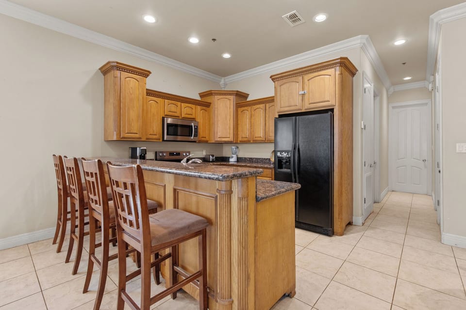 Fully equipped kitchen with granite countertops, ample cabinet storage, and breakfast bar seating