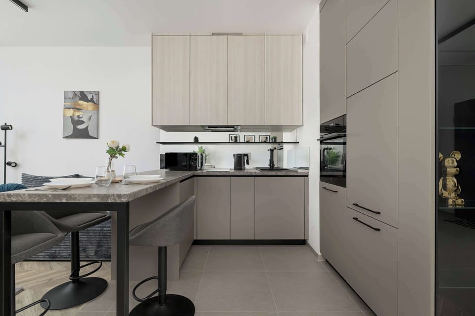 Another angle of the kitchenette highlighting clean countertops. Integrated appliances blend seamlessly with the cabinetry. The overall look is minimalist.