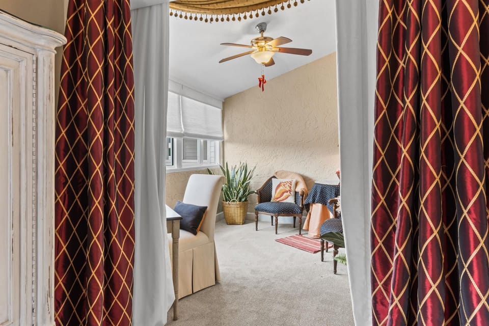 Step into your cozy living space where elegant patterned curtains frame comfortable seating and warm touches await your arrival.