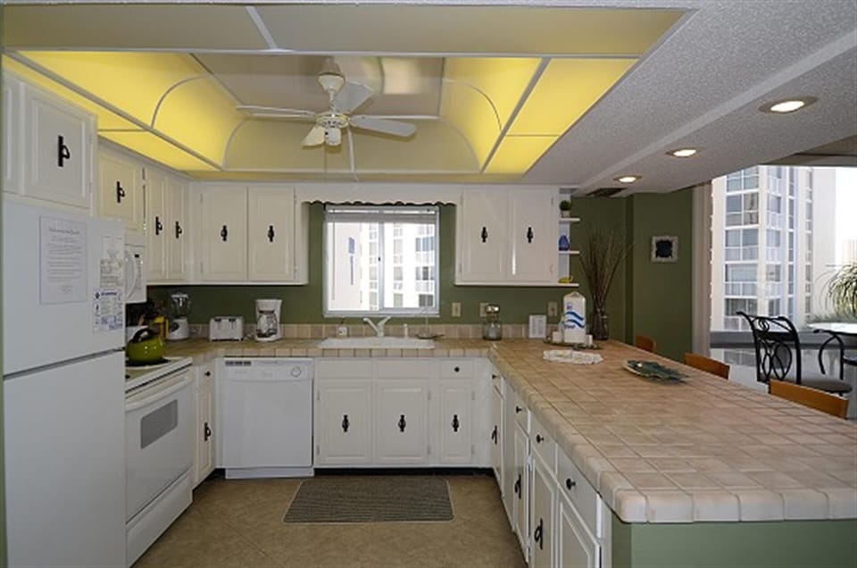 Cook your favorite meals in this spacious kitchen with tile counters, white cabinets, and city views.