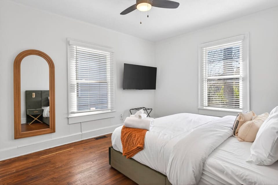 Premium King bed with luxurious linens, featuring a full length mirror, TV, and luggage rack to make for the ultimate bedroom