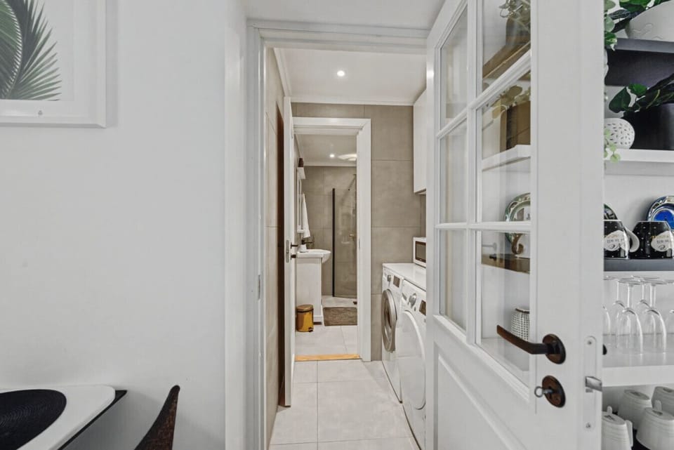 Dedicated laundry room with washer and dryer, connected to the bathroom featuring a walk-in shower. Practical for families and extended stays.