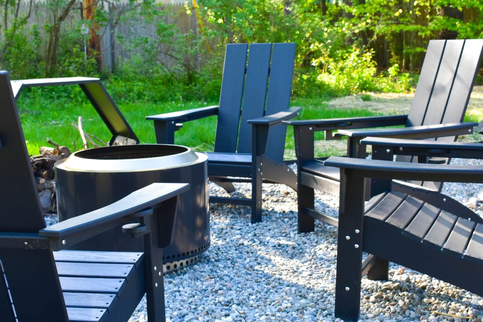 Solo Stove fire pit with Adirondack chairs on crushed stone with string lights and an open sky.