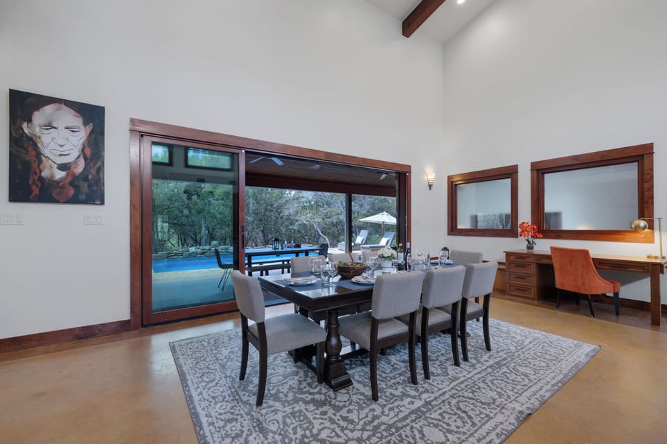 Gather around this elegant dining table with pool views through floor-to-ceiling windows, where memorable meals await in your sophisticated retreat.