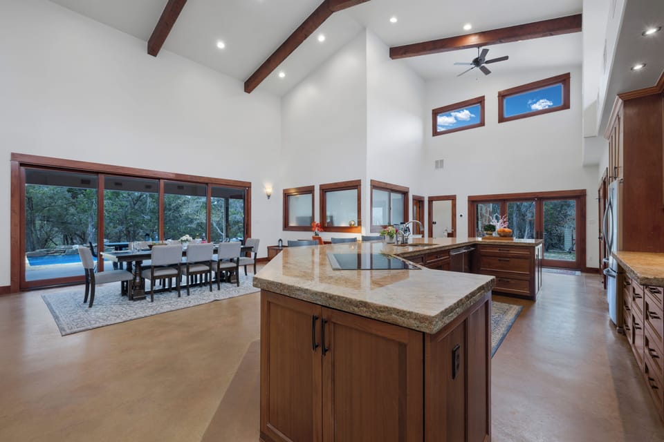 Cathedral beams, granite island, ten-seat dining, pool framed in glass