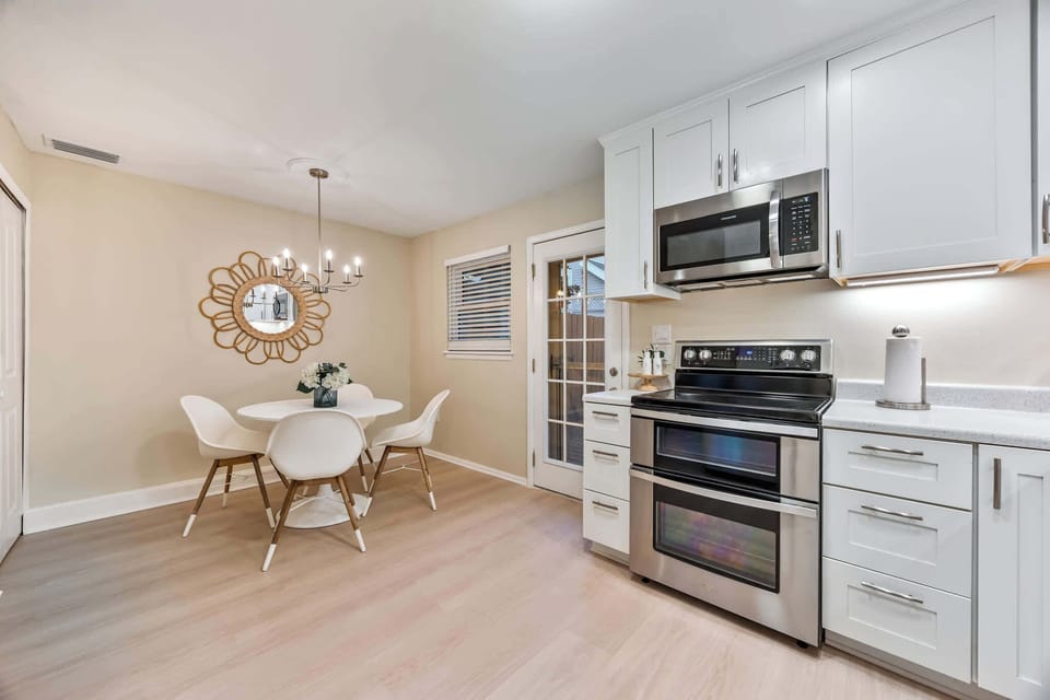 Modern kitchen and dining area with stainless steel appliances and a round table for four.