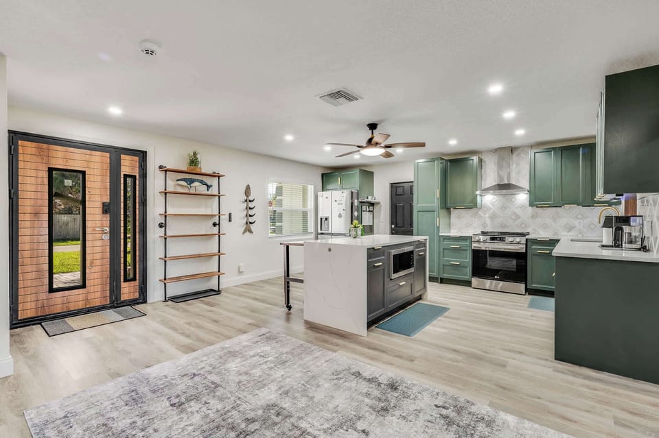 Open kitchen with green cabinetry and a central island under recessed lighting