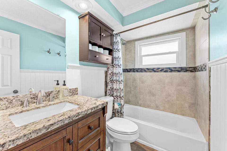 Bright bathroom with granite countertop and tiled bathtub surround