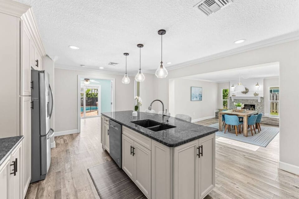 Modern kitchen with granite island and open dining area featuring a fireplace.