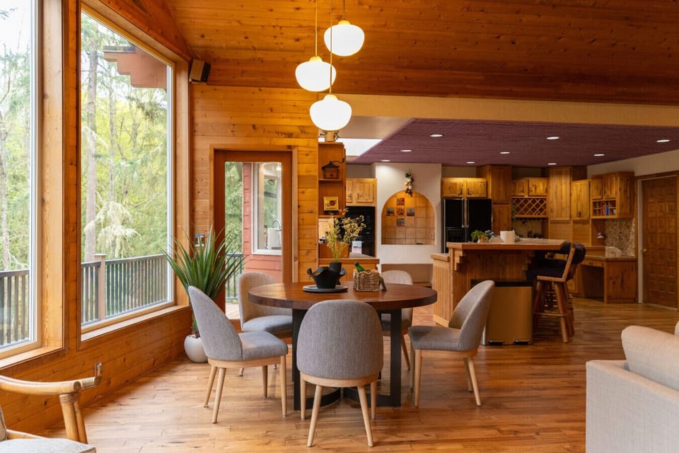 Sunlit dining space with forest views and seamless flow into the kitchen.