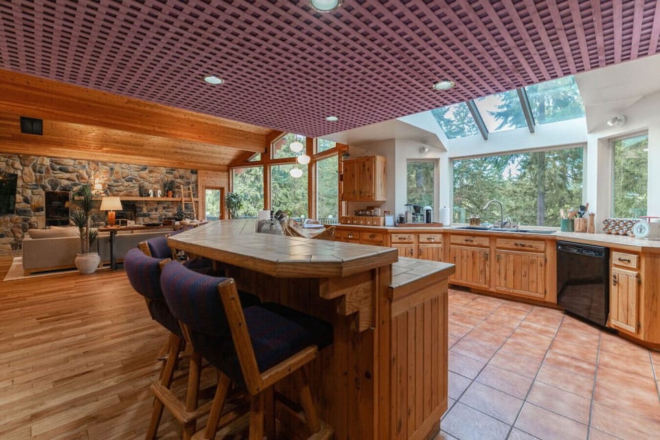 Spacious open-concept kitchen with large island skylights, and forest views.
