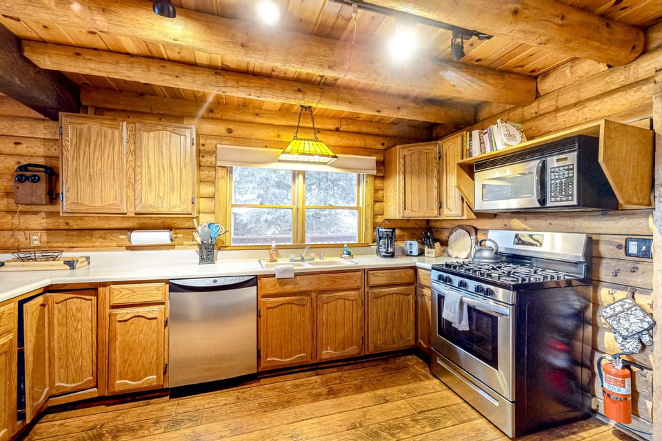 Oak cabinetry and warm wood tones frame this well-equipped kitchen, with a full-size oven, stovetop, and microwave ready for home-cooked meals after a day on the trails.