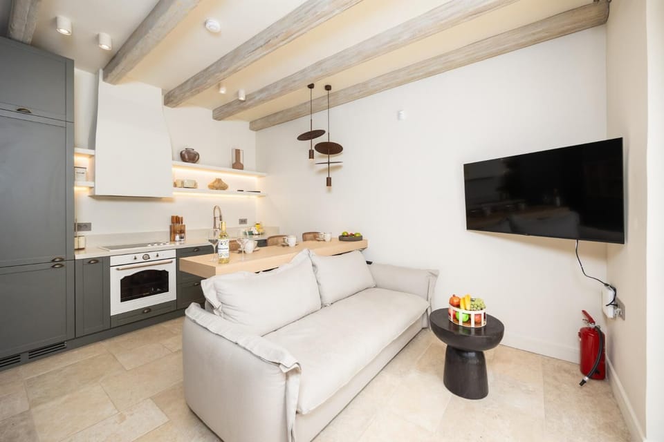 Open-plan living room with sofa, breakfast bar, kitchen, A/C, WiFi internet, and satellite TV